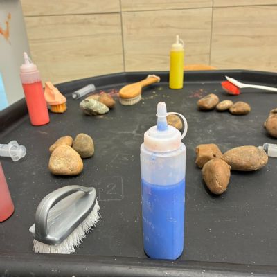 Paint in squeegee bottles, scrubbing brushes, and rocks